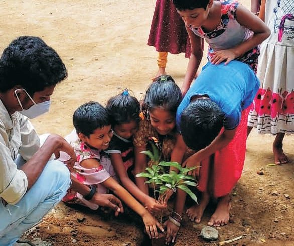 Volunteers and children planting saplings at a KUT tree plantation drive.